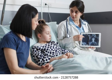 Healthcare Pediatric Clinic Radiology Expert Talking About X-ray Scan Results Of Ill Little Girl. Hospital Radiologist Analyzing Radiography Scan Image Results And Talking With Mother About Recovery.