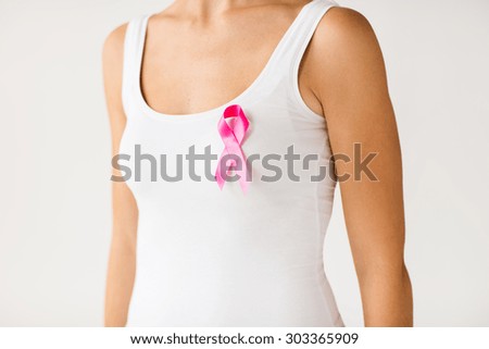 healthcare, people and medicine concept - close up of woman in white shirt with pink cancer awareness ribbon