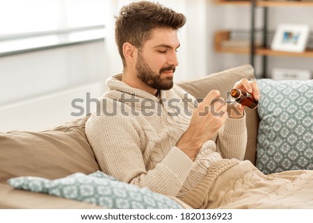 healthcare, people and medicine concept - sick man pouring antipyretic or cough syrup from bottle to spoon