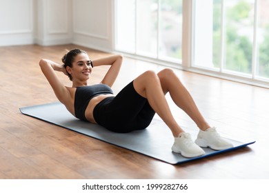 Healthcare, Physical Activity And Sports. Fit Young Lady Exercising At Fitness Club Studio Or Living Room Doing Sit-Ups Crunches Exercise Indoors Lying On Yoga Mat, Training Abdominal Muscles - Shutterstock ID 1999282766