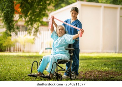 Healthcare or physical therapy nurse is helping elderly woman in performing a stretching or rehabilitation exercise with a resistance band caregiver individuals focused rehabilitation elderly concept. - Powered by Shutterstock