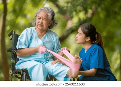 Healthcare or physical therapy nurse is helping elderly woman in performing a stretching or rehabilitation exercise with a resistance band caregiver individuals focused rehabilitation elderly concept. - Powered by Shutterstock