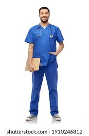 Healthcare, Profession And Medicine Concept - Happy Smiling Doctor Or Male Nurse In Blue Uniform With Stethoscope And Clipboard Over White Background