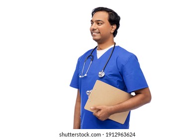 Healthcare, Profession And Medicine Concept - Happy Smiling Indian Doctor Or Male Nurse In Blue Uniform With Clipboard And Stethoscope Over White Background