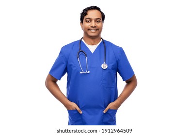 Healthcare, Profession And Medicine Concept - Happy Smiling Indian Doctor Or Male Nurse In Blue Uniform With Stethoscope Over White Background