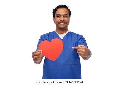 Healthcare, Profession And Medicine Concept - Happy Smiling Indian Doctor Or Male Nurse In Blue Uniform With Red Heart Over White Background