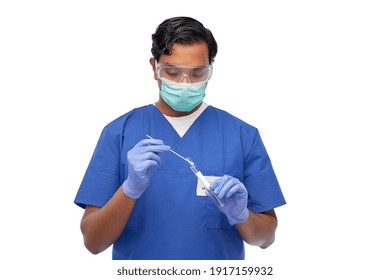 Healthcare, Profession And Medicine Concept - Indian Doctor Or Male Nurse In Blue Uniform, Face Mask For Protection From Virus, Goggles And Gloves With Cotton Swab And Test Tube Over White Background