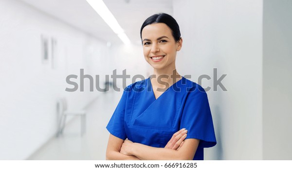 healthcare, profession, people and\
medicine concept - happy doctor or nurse at hospital\
corridor