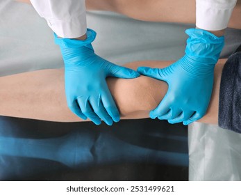 A healthcare professional examines a patient s knee joint using gloved hands in a medical setting during a routine assessment - Powered by Shutterstock