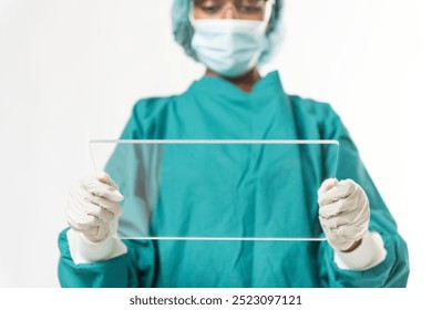 A healthcare professional in green scrubs and gloves holds a transparent tablet. The healthcare worker presenting on a screen. Medical, healthcare, professional. Surgeon presenting on screen. - Powered by Shutterstock