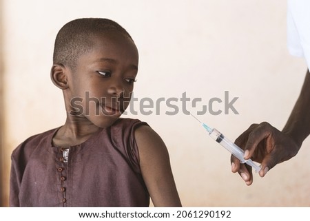 Healthcare professional holding a syringe with antimalarial vaccine to be injected to a small black African boy as part of a malaria control program - Malaria vaccination concept