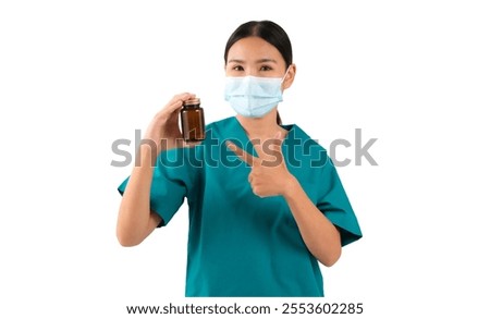 Healthcare professional in scrubs holding a medicine bottle and pointing, isolated on white background.