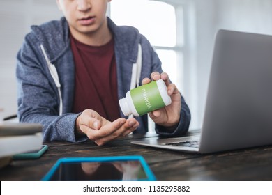 Healthcare. Serious Young Man Sitting At The Table And Taking Vitamin D