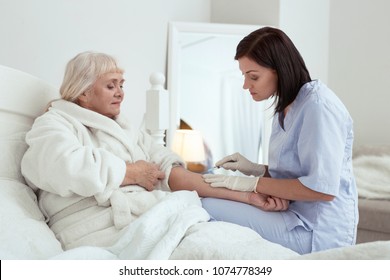 Healthcare service. Pretty attractive nurse using syringe while treating elder woman - Shutterstock ID 1074778349