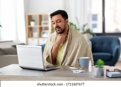 Healthcare, Technology And People Concept - Sick Indian Man In Blanket With Sore Throat Having Video Call On Laptop Computer At Home