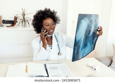 Healthcare, technology, roentgen, people and medicine concept - young female doctor in white coat with laptop computer looking at x-ray in medical office while talking via phone.  - Powered by Shutterstock