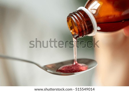 healthcare, treatment and medicine concept - bottle of medication or antipyretic syrup and spoon