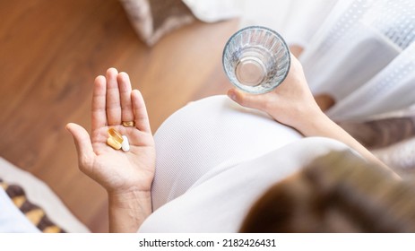Healthcare, treatment, supplements. Happy smiling woman taking pill with supplement vitamin Omega 3. Pregnancy, medicine health care concept - Shutterstock ID 2182426431