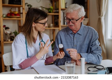 Healthcare Worker Or Caregiver Visiting Senior Man Indoors At Home, Explaining Medicine Dosage.