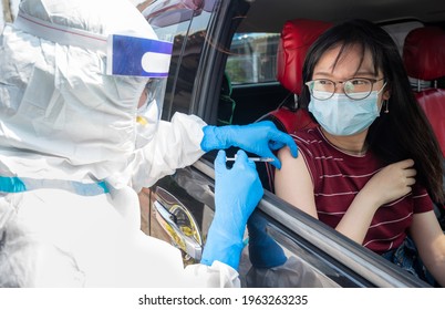 Healthcare Worker Giving Shot Of Covid-19 Vaccine To Patient's Shoulder In COVID-19 Drive-thru Detection Site.