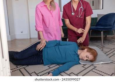 A healthcare worker instructs in CPR on a mature woman, as another adult looks on. - Powered by Shutterstock