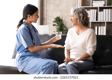 Healthcare worker or nurse caregiver giving pills, showing a prescription drug to senior woman. Elderly healthcare concept - Powered by Shutterstock