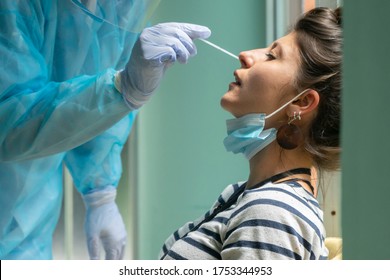 Healthcare worker with protective equipment performs coronavirus swab on Caucasian girl.Nose swab for Covid-19. - Shutterstock ID 1753344953