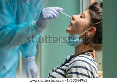 Healthcare worker with protective equipment performs coronavirus swab on Caucasian girl.Nose swab for Covid-19. Foto d'archivio © 