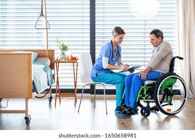 A healthcare worker and senior patient in wheelchair in hospital, talking.