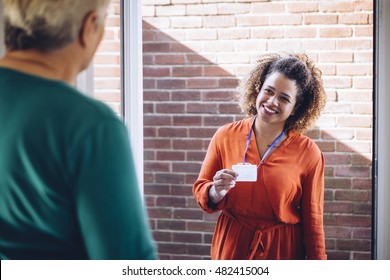 Healthcare worker showing her badge at the front door of a senior womans home.  - Powered by Shutterstock