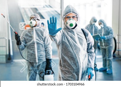 Healthcare worker showing stop gesture. Team of healthcare workers wearing hazmat suits working together in shopping centre, to control an outbreak of virus in the city