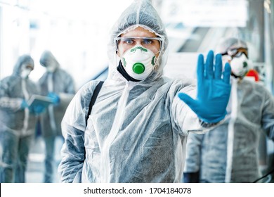 Healthcare worker showing stop gesture. Team of healthcare workers wearing hazmat suits working together in shopping centre, to control an outbreak of virus in the city - Shutterstock ID 1704184078