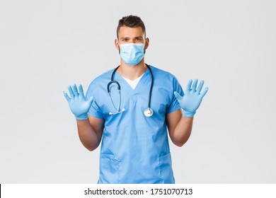 Healthcare Workers, Covid-19, Coronavirus And Preventing Virus Concept. Serious-looking Hispanic Doctor, Male Nurse In Scrubs, Medical Mask, Showing Gloves On Hands, Ask Wear Protective Equipment