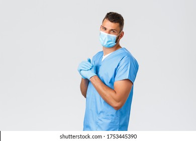 Healthcare Workers, Covid-19, Coronavirus And Preventing Virus Concept. Handsome Doctor, Male Nurse In Medical Mask And Scrubs, Crack Knuckles, Night Shift At Clinic, Grey Background