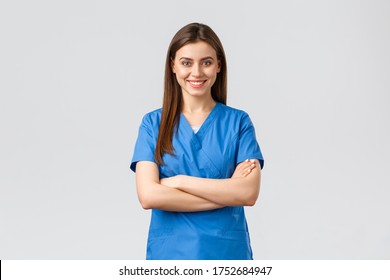 Healthcare workers, prevent virus, insurance and medicine concept. Confident female doctor, nurse in blue scrubs, smiling and cross arms chest, ready to save patient lives, grey background - Powered by Shutterstock