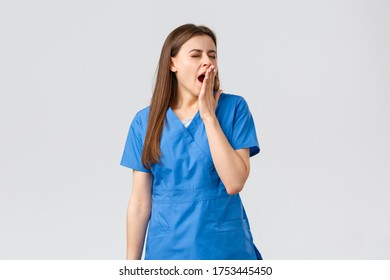 Healthcare Workers, Prevent Virus, Insurance And Medicine Concept. Tired Young Female Nurse Had Tough Night Shift At Hospital, Yawning, Cover Opened Mouth With Palm, Feel Sleepy, Lack Energy