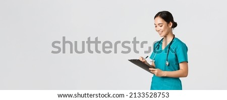 Healthcare workers, preventing virus, quarantine campaign concept. Beautiful smiling asian doctor, nurse running checkup in hospital, looking at clipboard with patient results, examine people