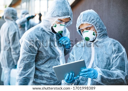 Healthcare workers wearing hazmat suits working together to control an outbreak