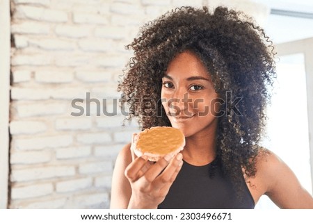 Health-conscious young woman in sportswear enjoys a nourishing rice cake with peanut butter, embracing a healthy diet.