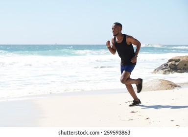 Healthy active african american man running by water on the beach