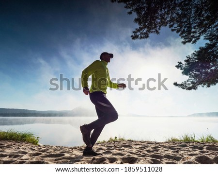Healthy and active lifestyle, sport concept. Slim fitness sportsman, athletic wear black male  long tights and yellow long sleeve jersey., Stock photo © 