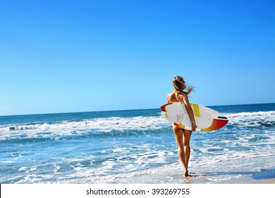 Healthy Active Lifestyle. Surfing. Water Sports. Beautiful Athletic Surfer Woman With Sexy Fit Body In Bikini With Surf Board Walking On Sea Beach. Summer Vacation. Extreme Sport. Summertime Fun Hobby