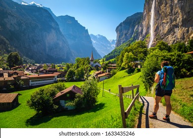 Healthy active woman hiker with colorful backpack, enjoying the view in Lauterbrunnen village. Popular hiking place with waterfalls and mountains, Switzerland, Bernese Oberland, Switzerland, Europe