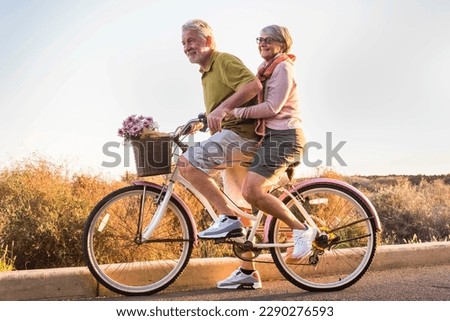 Healthy ad active mature retired people lifestyle. Man carrying woman senior aged on the same bike. Retired people having fun in outdoor leisure activity. Togetherness concept life. Happiness. Youthfu