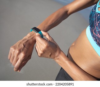 Healthy African American Girl In Sports Clothing Using Wearable Technology To Monitor Fitness Activity During Workout On Beach