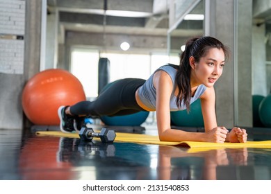 Healthy Asian Athlete Woman In Sportswear Do Plank Workout Exercise Body Weight Lifting At Fitness Gym. Strong Female Body Building Muscle Weight Training At Sport Club. Health Care Motivation Concept