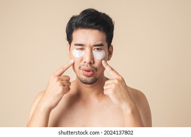 Healthy Asian Man Pointing Show Patches Mask Under Eyes For Anti Wrinkles And Eye Dark Circles On Face. Isolated On Brown Color Background.
