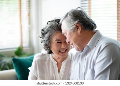 Healthy Asian Older People Laughing And Relaxing At Their House Together. Happy Smiling Elderly Man And Woman Celebrating Anniversary. Joyful Senior Couple In Love. Copy Space.