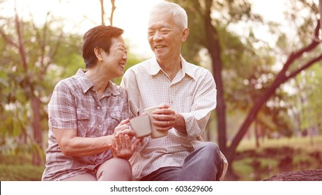 Healthy Asian Senior Couple Drinking Coffee In Morning Park Together