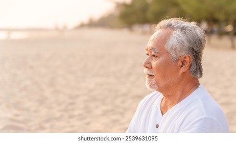 Healthy Asian senior man enjoy outdoor lifestyle travel nature ocean on summer vacation. Elderly man relaxing with meditation and yoga on the beach at sunset. Health care motivation concept. - Powered by Shutterstock